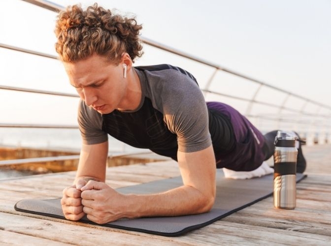 Man performing planks on a bridge